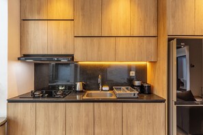 Une cuisine moderne avec des meubles en bois, une cuisinière noire, un évier en acier inoxydable et un réfrigérateur GE.