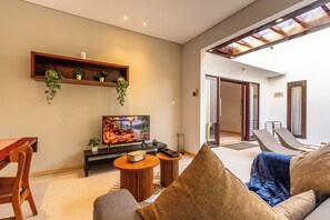 Un salon moderne doté d’un téléviseur à écran plat, de meubles en bois et offrant une vue sur l’extérieur.
