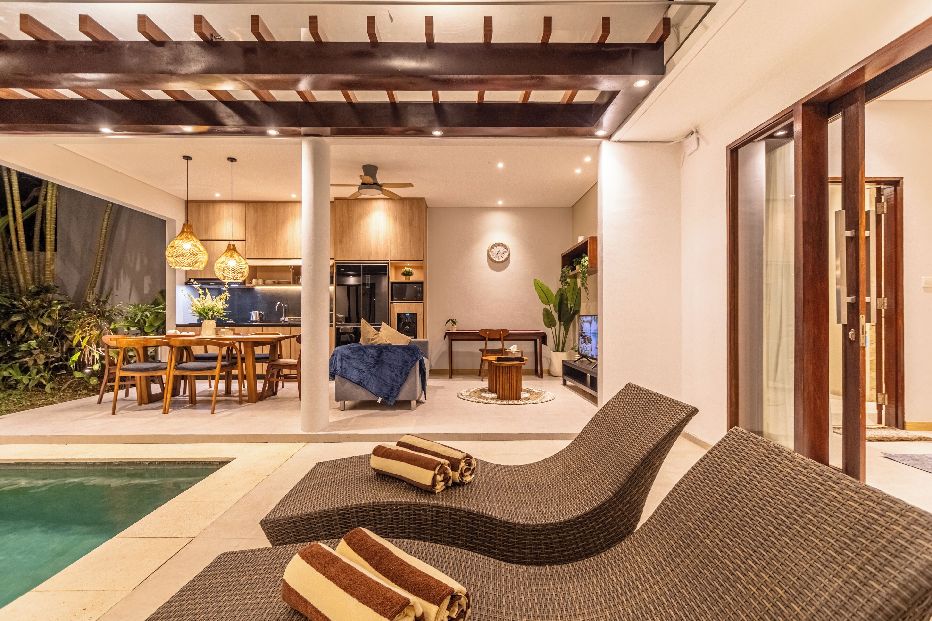 Uma área externa moderna com piscina, espreguiçadeiras e espaço para refeições.