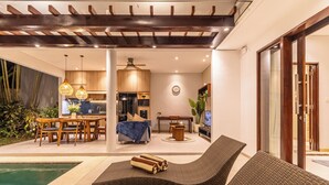 A modern outdoor living area with a pool, lounge chairs, and a dining setup.