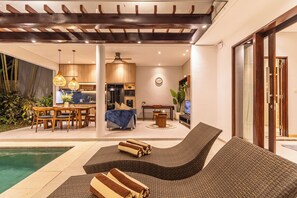 Un espace de vie extérieur moderne comprenant une piscine, des chaises longues et un coin repas.