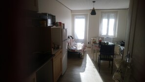 Eine kompakte Küche mit Kühlschrank, Mikrowelle und Spüle. Ein Essbereich mit Tisch und Stühlen, sowie ein Fenster für natürliches Licht.