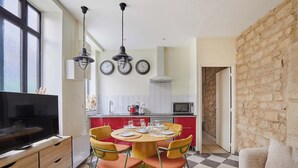 Uma cozinha moderna com área de jantar, destacando um piso xadrez, uma mesa redonda com cadeiras e uma televisão.