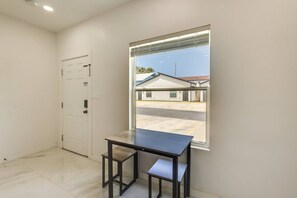 Una habitación con una mesa, una puerta y una ventana que da a un edificio y una calle.