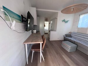 A compact living space with a dining area, a sofa, and a ceiling fan. - Stintino - Anna Apartment - Residential Area (Stintino)