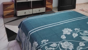 Um quarto com cama, televisão, guarda-roupa, porta e um quadro na parede.
