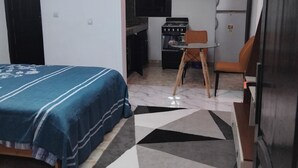 Quarto compacto com cama, cozinha compacta e área de refeições.