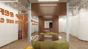 A modern interior with a curved seating area, wooden panel walls, and a glass partition with orange text.