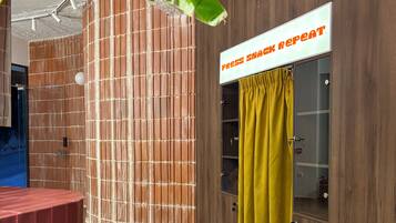 A room with a wooden wall, a yellow curtain, and a sign that reads 'Press Snack Repeat'.