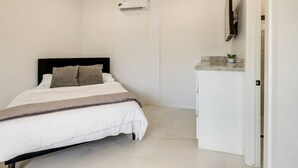 Ein Schlafzimmer mit einem Bett, einem weißen Kleiderschrank und einer Klimaanlage.