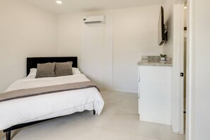 A bedroom with a bed, a white wardrobe, and an air conditioning unit. - Studio #3 | Island Time Studio w/Pool, near Beach (South Padre Island)