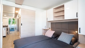 A modern bedroom with a large bed, built-in shelving, and a view to a balcony. - Exclusive Houseboat With hot tub (Piran)