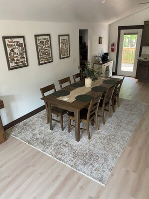 A dining area with a wooden table and chairs, a patterned rug, and three framed pictures on the wall. - Newly renovated home ,  River access,  minutes to Glacier Park (Columbia Falls)