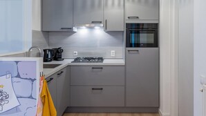 A compact kitchen with grey cabinets, a built-in oven, and a gas stove. - Villa in Hoogerheide With Private Terrace (Hoogerheide)