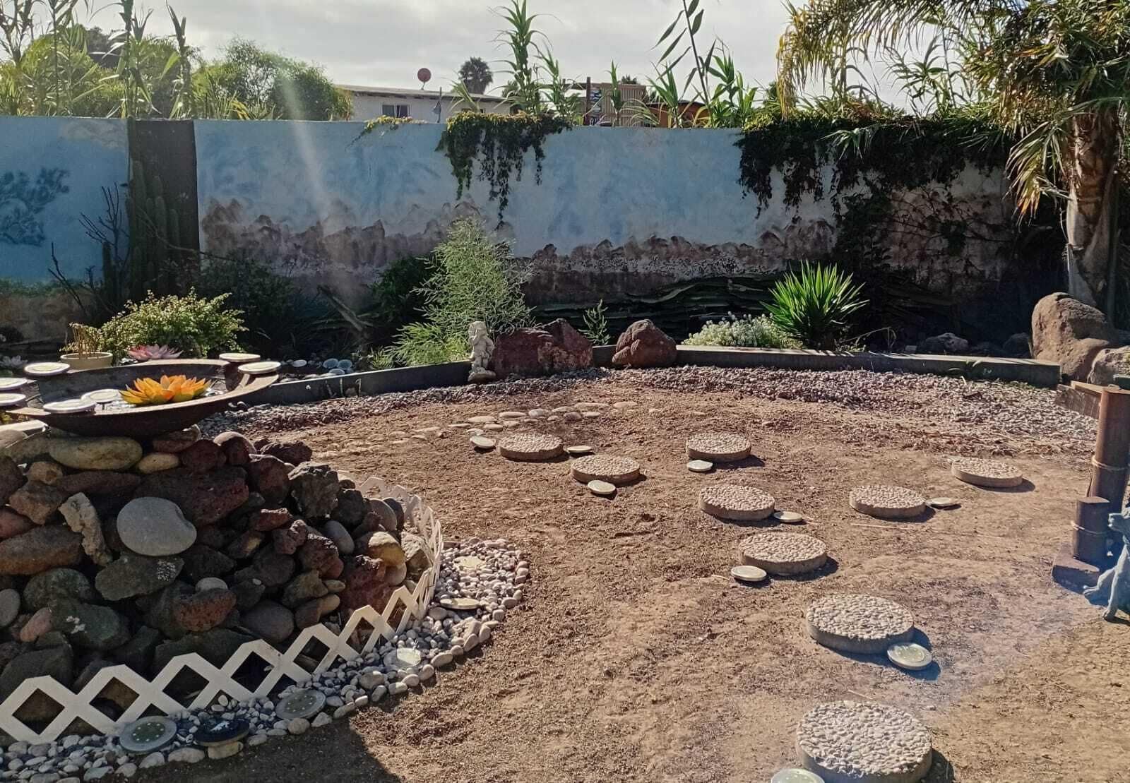 A circular outdoor area with a central water feature, surrounded by rocks and pebbles.