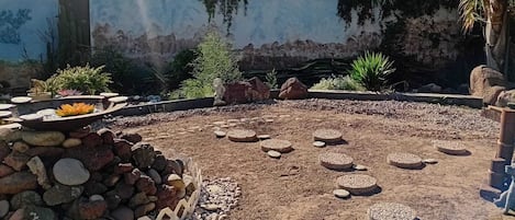 A circular outdoor area with a central water feature, surrounded by rocks and pebbles.