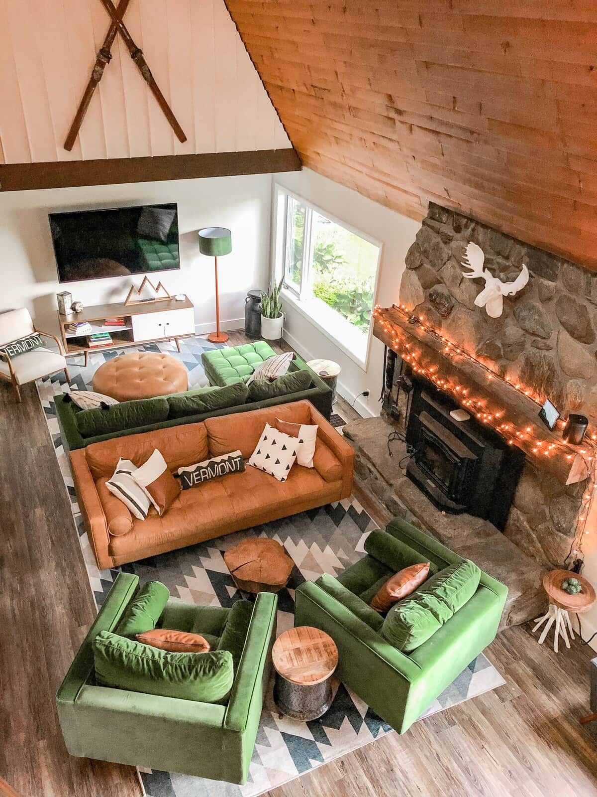 A cozy living room with a fireplace, green sofas, a television, and a stone wall.