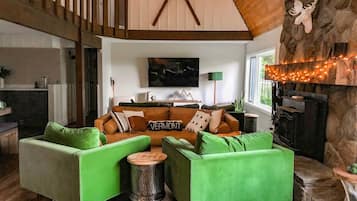 Un salon chaleureux avec un canapé vert, une cheminée et un mur en pierre.