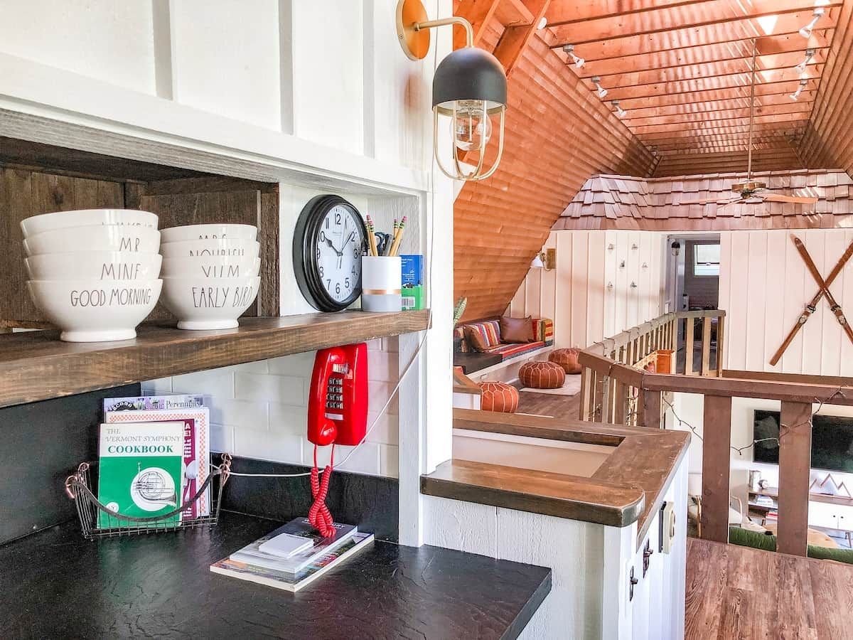 A kitchen with a wooden countertop, a red telephone, and a clock.