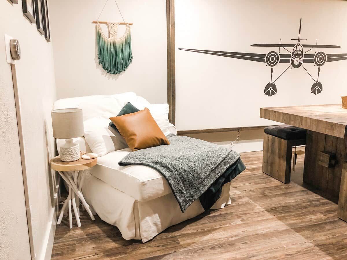 Une chambre à coucher avec un lit, une table de chevet, une lampe et un motif décoratif sur le mur.