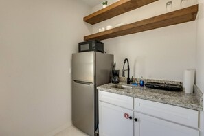 Eine kleine Küche mit einem Edelstahl-Kühlschrank, einem Spülbecken mit Armatur und einem Herd.