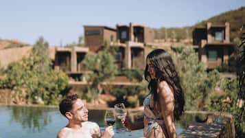 Um casal em uma piscina com um edifício moderno ao fundo.