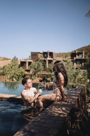 A couple in a swimming pool with a modern building in the background.