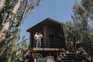 A wooden cabin with a balcony, surrounded by trees and rocks. - Come stay with us!!! (B.C.)