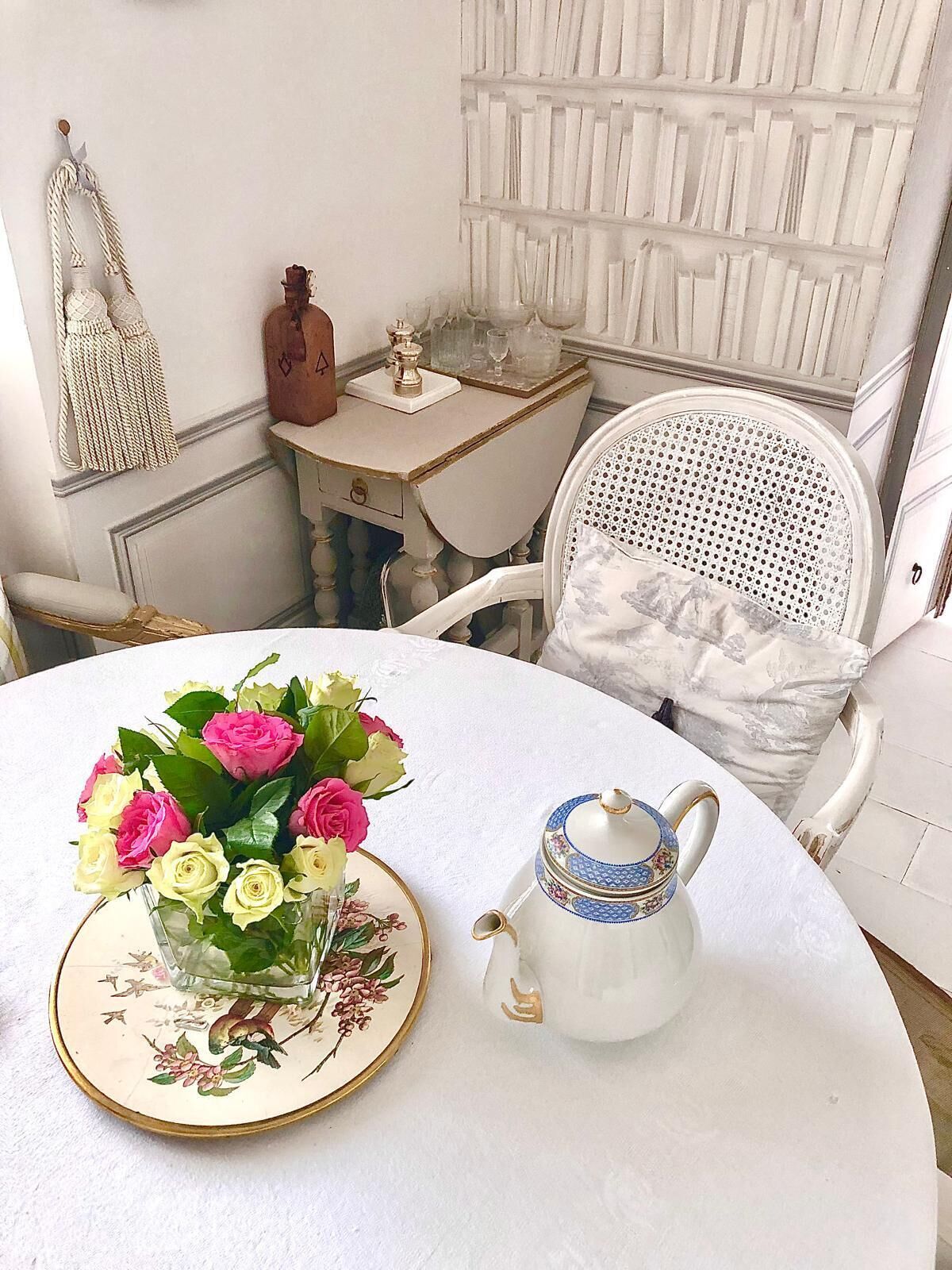 A round table with a floral vase and a decorative teapot.