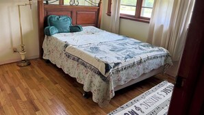 A bedroom with a wooden bed, a floor lamp, and a window with curtains.
