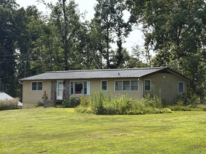 A single-story house with a gabled roof, a front porch, and a small front yard. - Tranquil 3-bedroom house with AC in charming Bloomington (Bloomington)