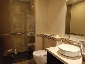 Ein modernes Badezimmer mit einer Glaskabine zur Dusche, einer weißen Toilette und einem großzügigen Waschtisch.