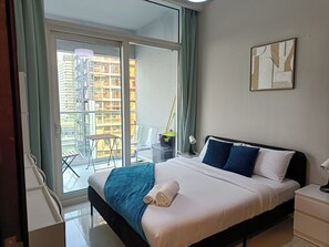 Ein Hotelzimmer mit einem Bett, einem Nachttisch, einem Sessel, einem Fenster mit Blick auf Gebäude und einem Vorhang.