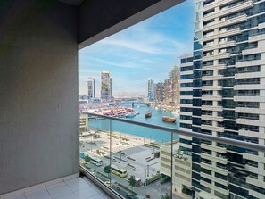A high-rise building with a view of a marina and cityscape. - Canal Front 1BHK 5-Star Facilities Business Bay (Dubai)
