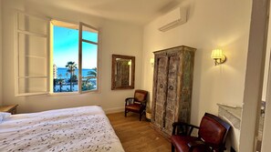 A room with a bed, a chair, a wardrobe, and a view of the sea. - Sea View 1-bedroom apartment with AC in charming Cannes (Cannes)