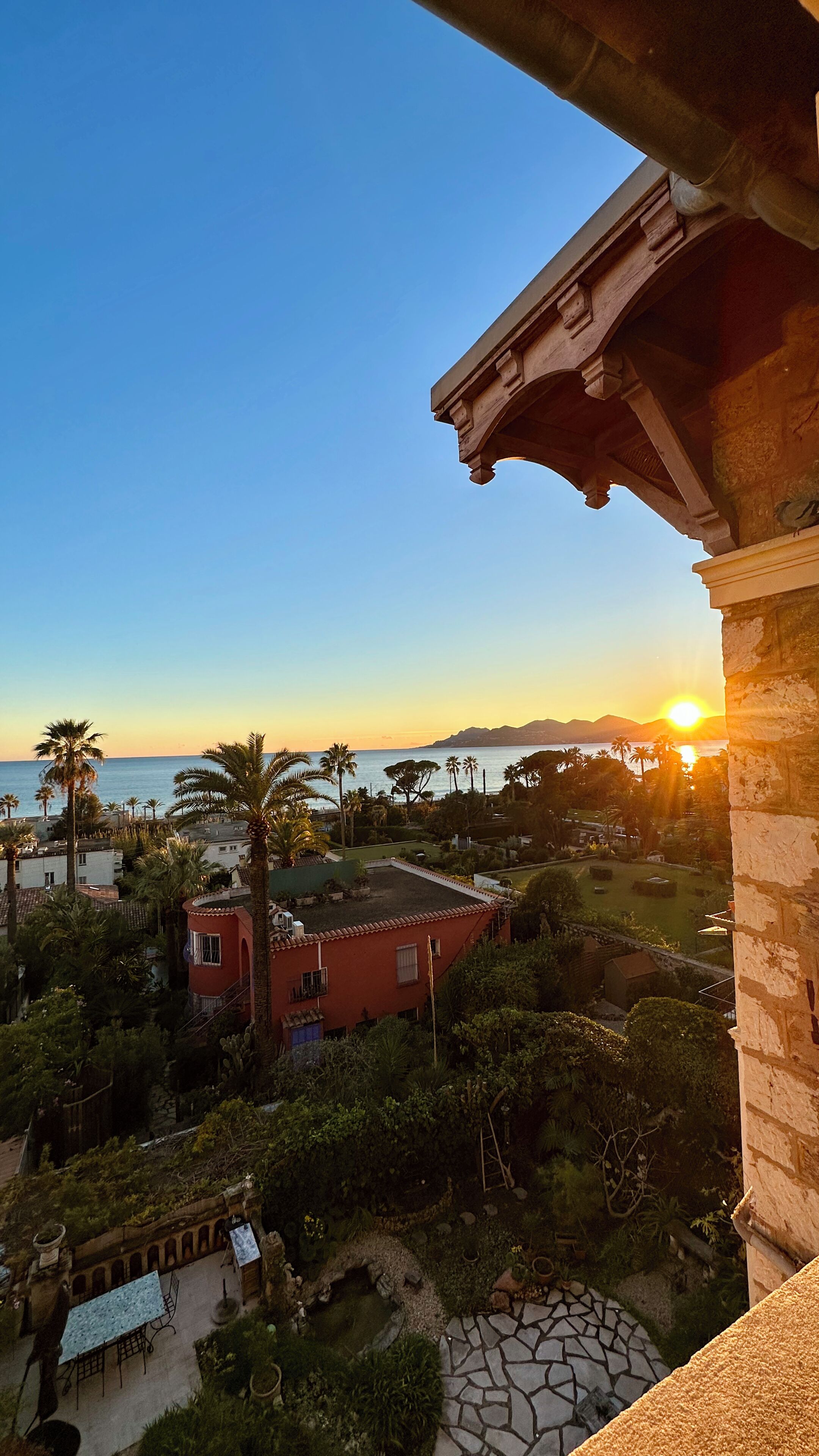 A residential area with a view of the sea and mountains during sunset.