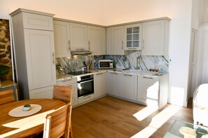 A compact kitchen with white cabinets, a microwave, an oven, and a marble backsplash. - Sea View 1-bedroom apartment with AC in charming Cannes (Cannes)