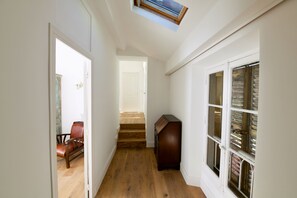 A hallway with a wooden floor, a chair, a cabinet, and a window with blinds. - Sea View 1-bedroom apartment with AC in charming Cannes (Cannes)