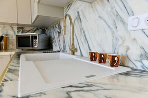 A kitchen with a built-in sink, a microwave, and a marble backsplash. - Sea View 1-bedroom apartment with AC in charming Cannes (Cannes)