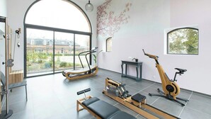 Quarto espaçoso com uma grande janela, equipamentos de ginástica e vista para uma área residencial.