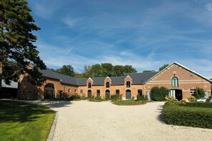 Ein Backsteinhaus mit Kiesweg und einem großen Baum links.