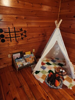 Een houten interieur met een witte tent, een boekenkast en een vloerkleed.