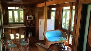 A wooden interior with a dining table, chairs, a refrigerator, and a television. - Villas de la Bahía Playa Tambor (Cobano)