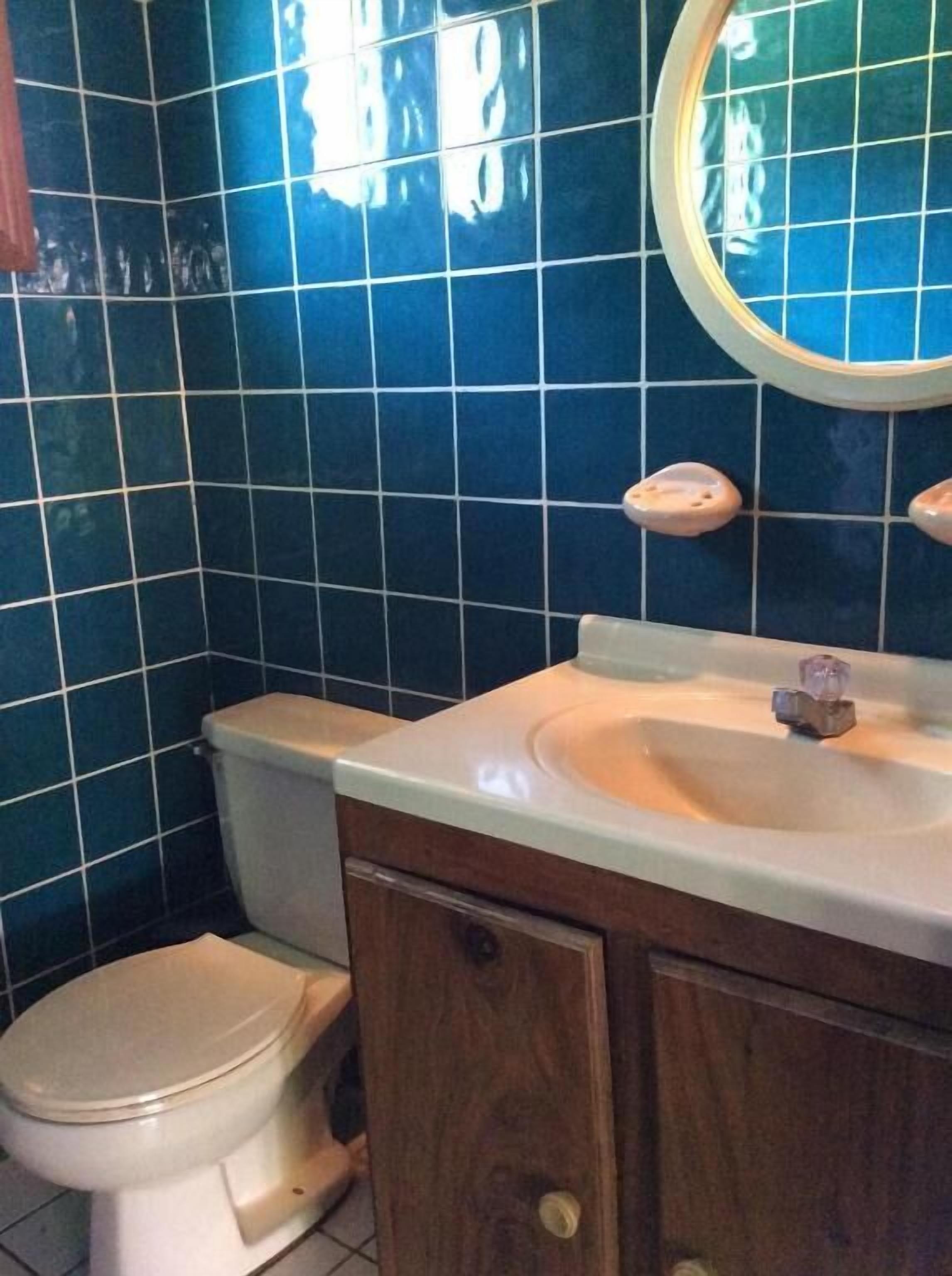 A bathroom with a toilet, sink, and mirror.