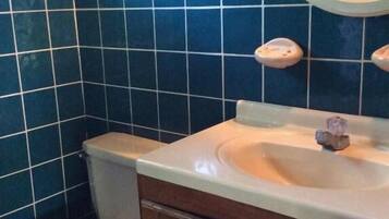A bathroom with a toilet, sink, and mirror.