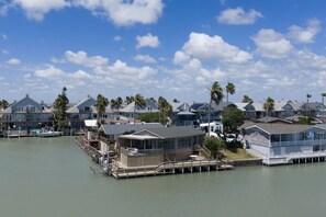 A waterfront property with multiple houses, docks, and a clear sky. - Oyster Cove in Long Island Village (Port Isabel)