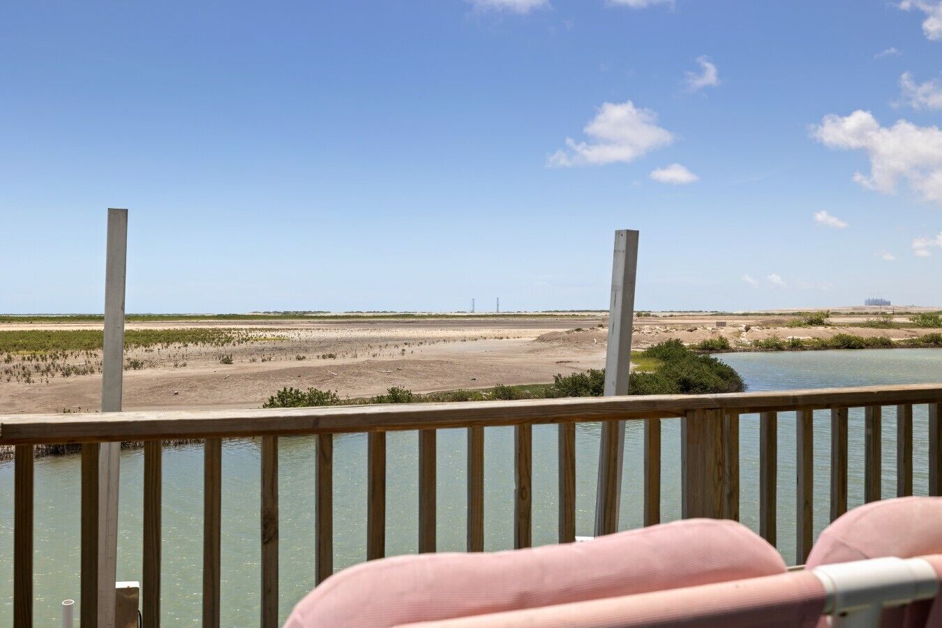 Blick von einem Balkon auf einen Fluss mit sandigem Ufer und spärlicher Vegetation.