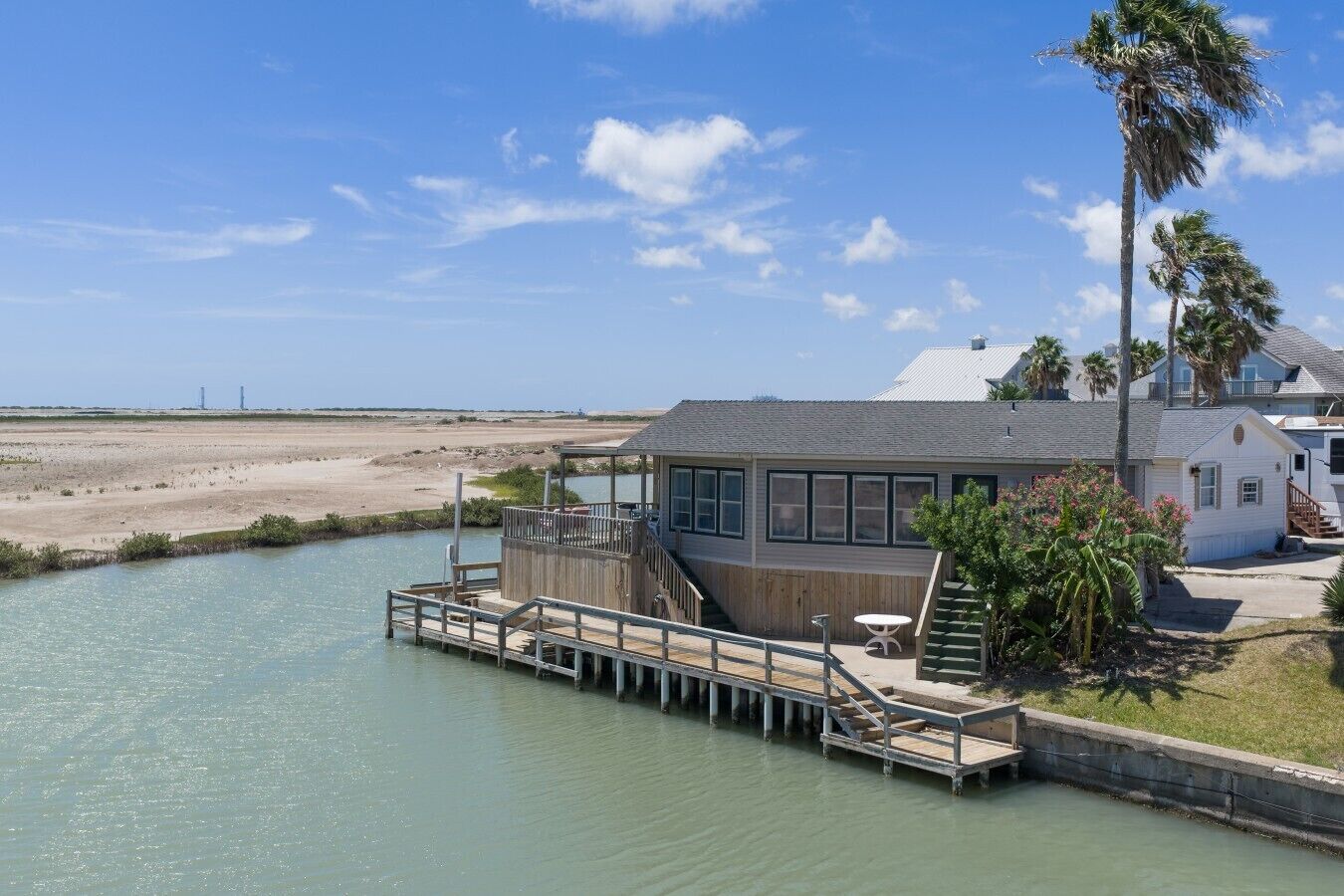 A waterfront property with a dock, a house, and a beach in the background.