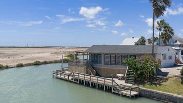 A waterfront property with a dock, a house, and a beach in the background.