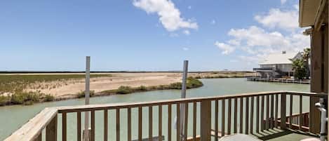 A wooden deck with a view of a water body and a distant building.